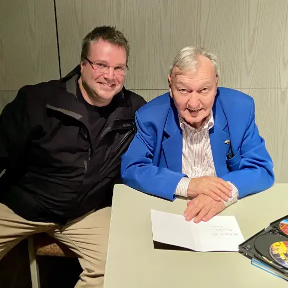 Erich von Däniken und Frank Burek gemeinsam sitzend am Tisch.